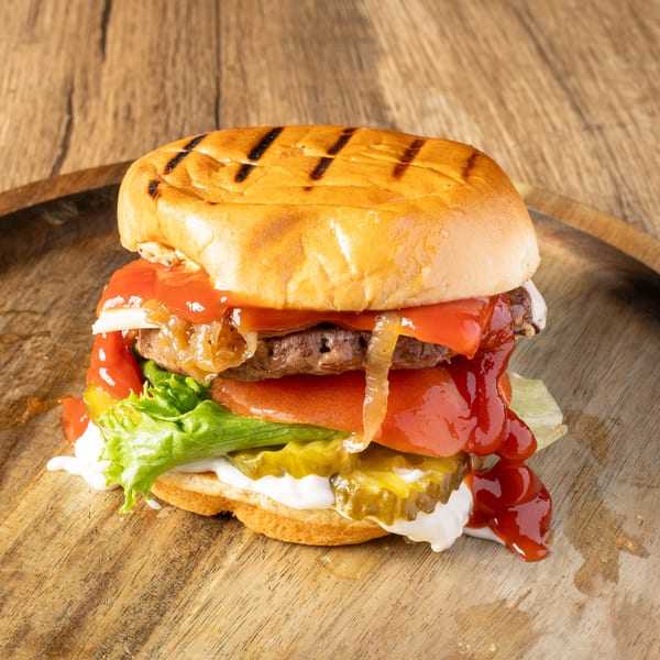 A juicy burger with grilled bun, lettuce, tomato, pickles, caramelized onions, ketchup, and mayonnaise.