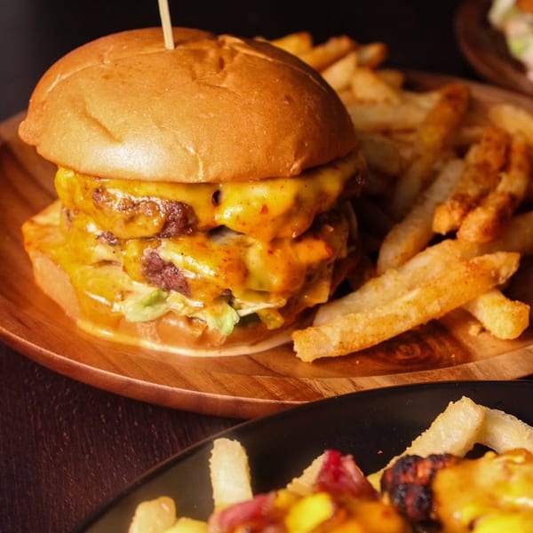 A juicy double cheeseburger with melted cheese and a skewer, served with crispy fries.